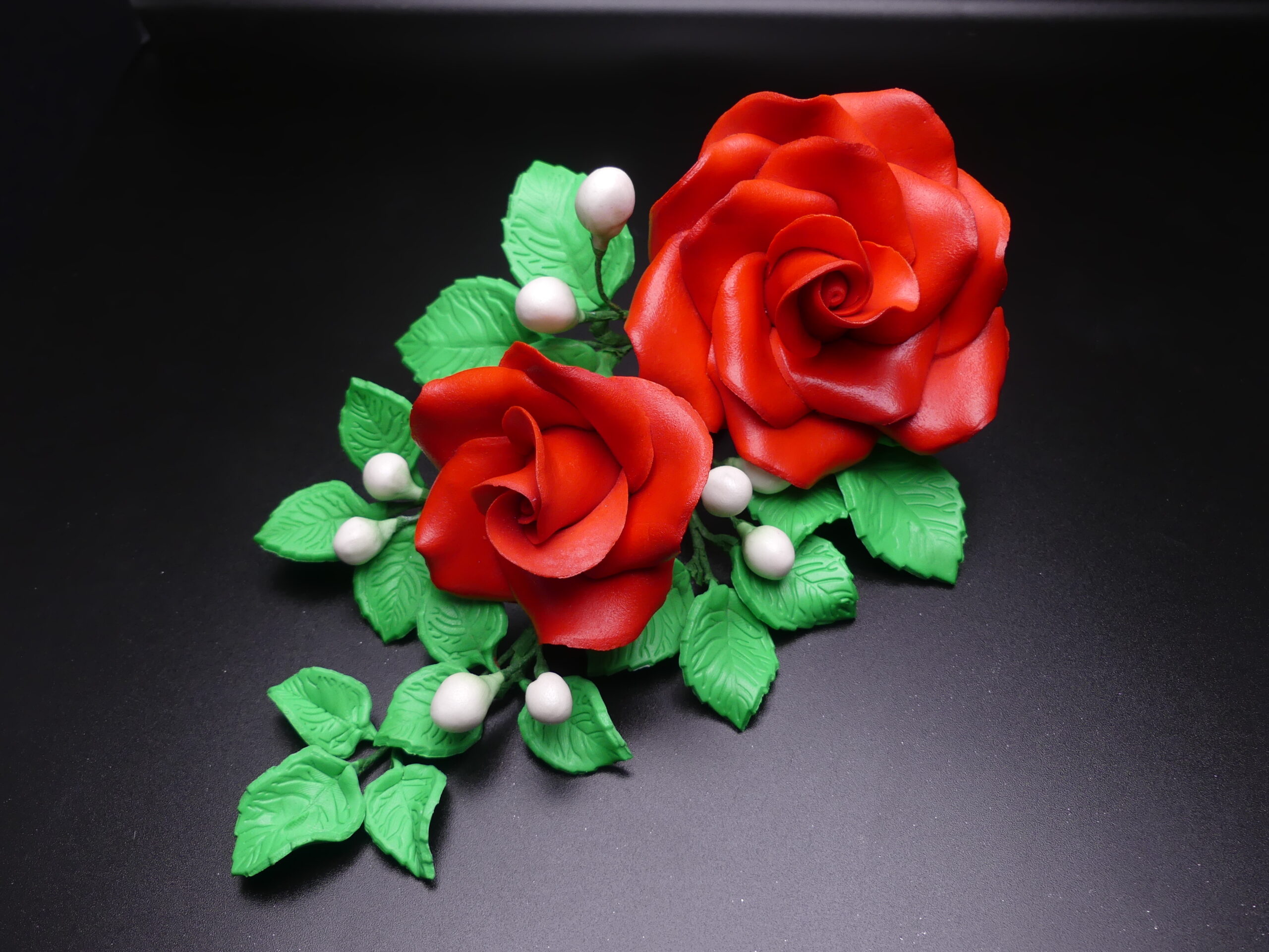 Cake Topper with red roses, green leaves and small white berries.