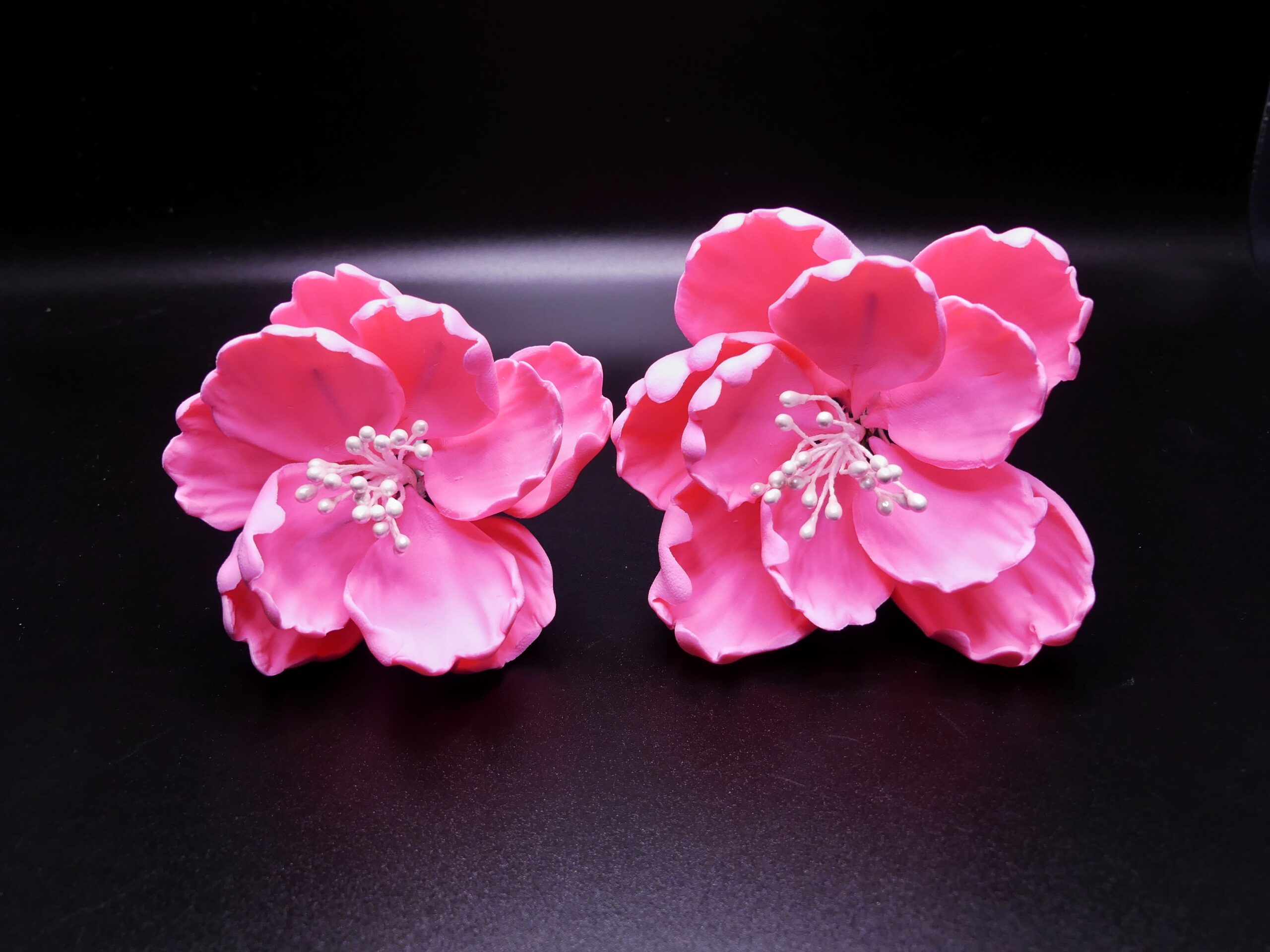 A set of 1 small and 1 medium, pink colored peonies with white stamens.
